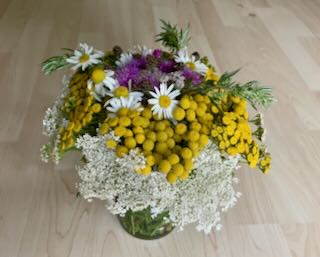 Einfacher, kostenloser, weil selbst am Wegrand gepflückter Blumen- und Kräuterstrauß in einem leeren Schraubglas zum 12. Juli, Tag der Einfachheit