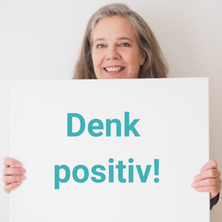 Foto von lächelnder Sabine Musseleck mit Schild mit der Aufschrift "Denk positiv!" zum 13. September (Tag des positiven Denkens)