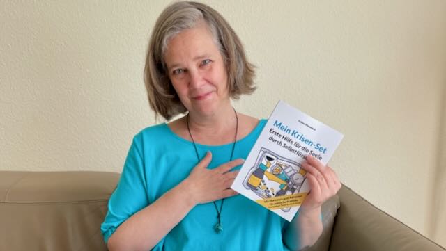 Foto von Sabine Musseleck mit dem Ratgeber "Mein Krisen-Set"